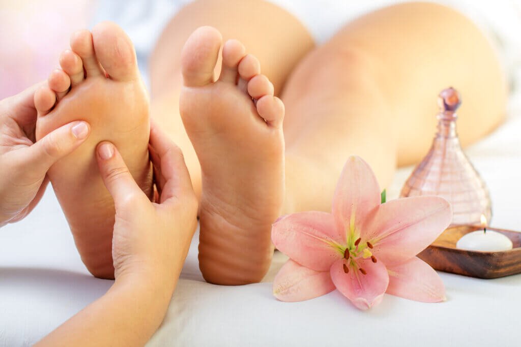 Mains pratiquant une pression de réflexologie plantaire sur un pied